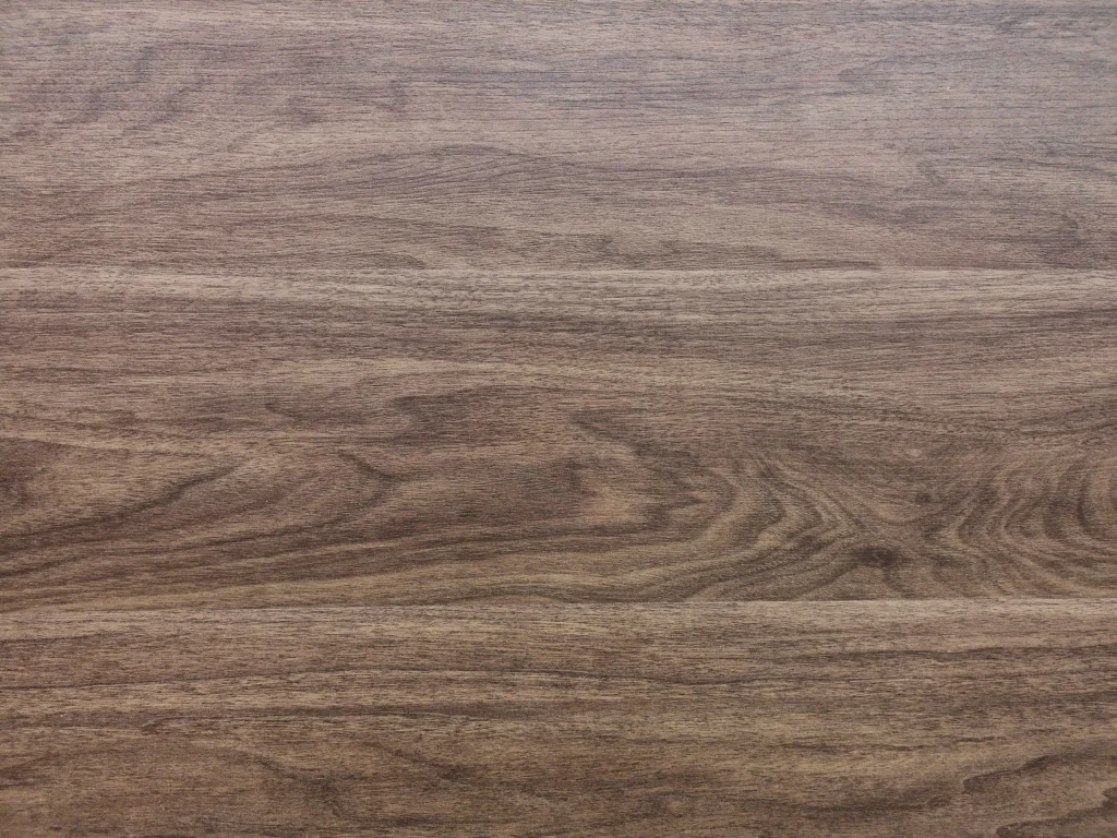 Gray-brown wood surface showing subtle grain patterns and natural variations in color.