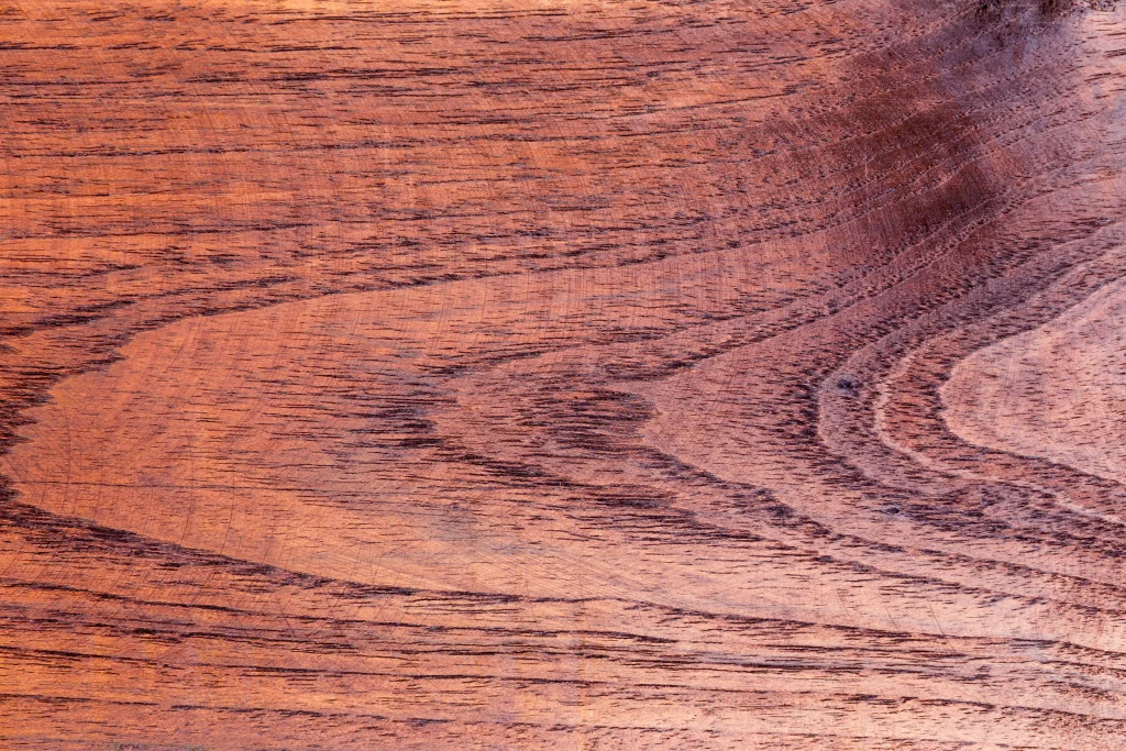 Close-up of reddish-brown hardwood featuring dark grain lines and natural wood texture.